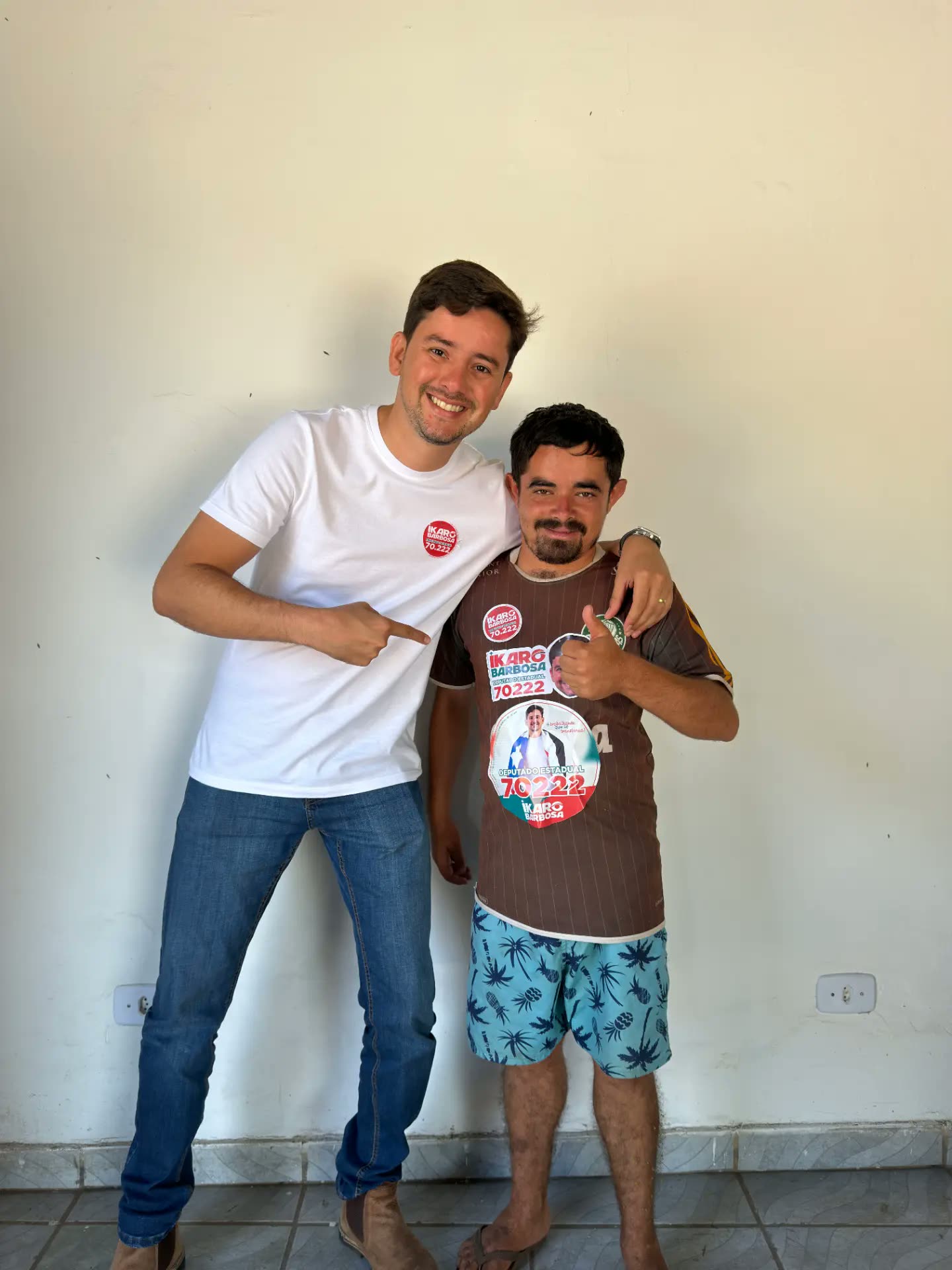 Ikaro Barbosa ao lado de um apoiador com adesivos da campanha