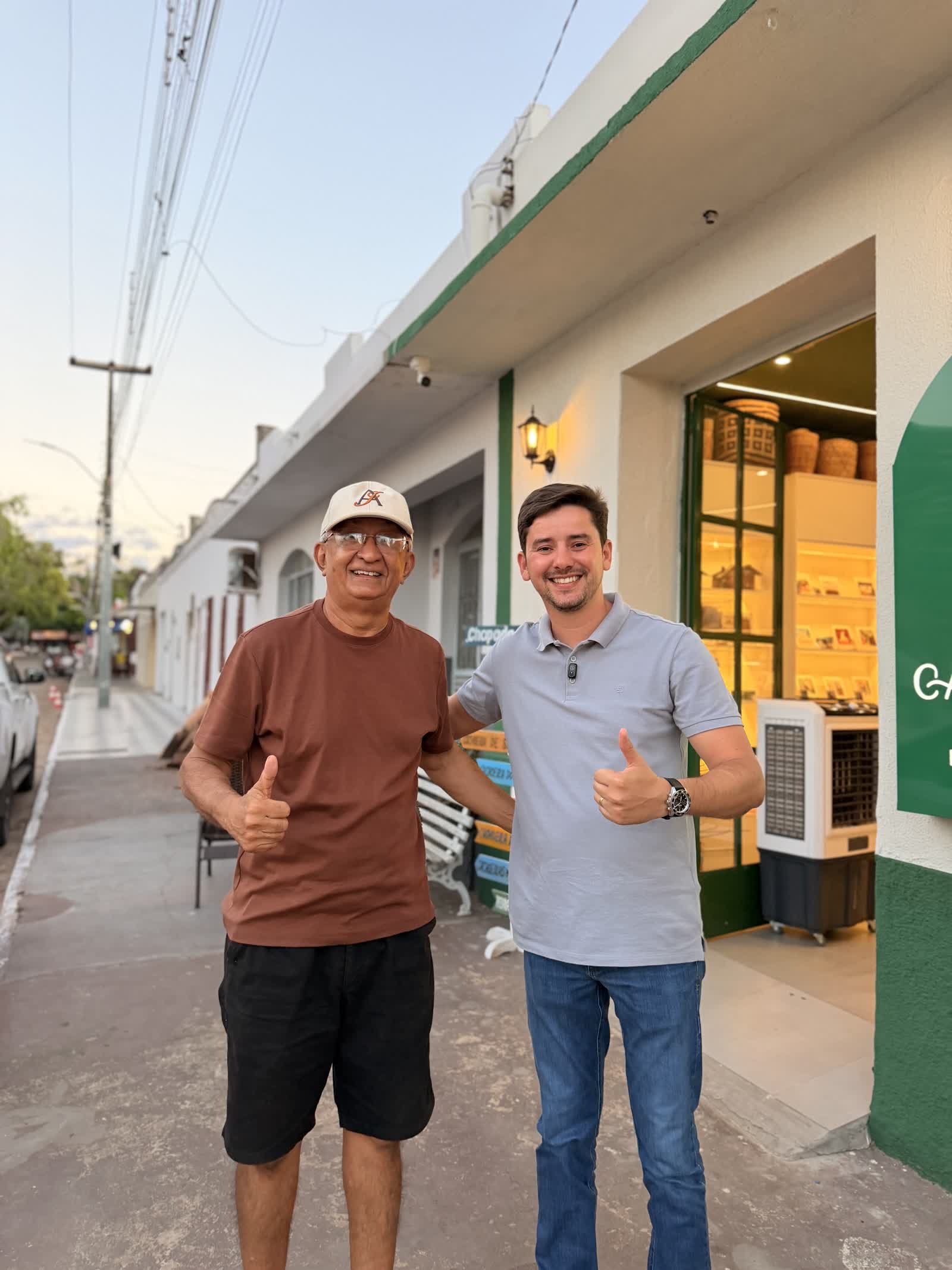 Ikaro Barbosa ao lado de um apoiador em frente ao comércio local