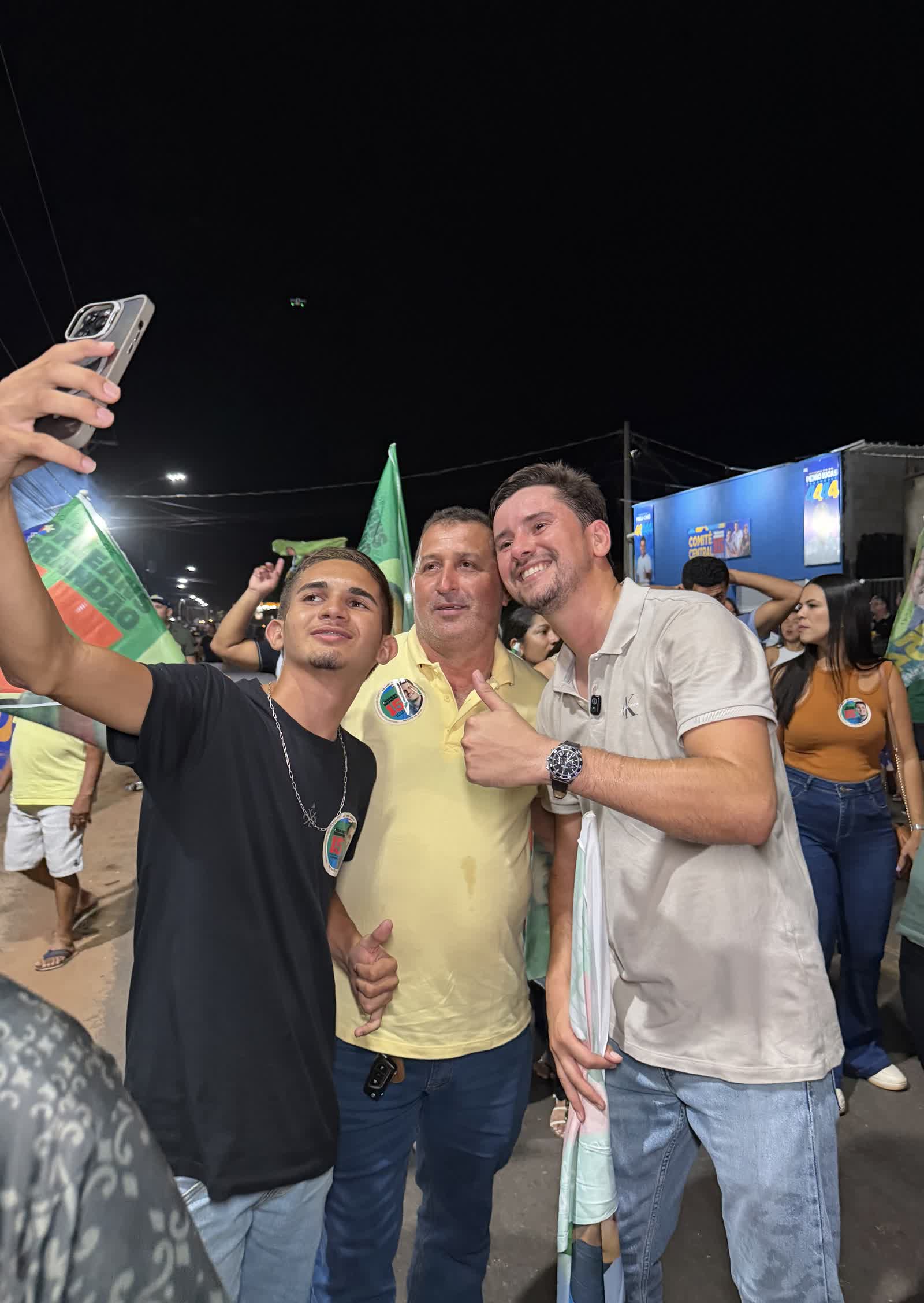 Ikaro Barbosa em selfie com apoiadores em caminhada noturna com bandeiras