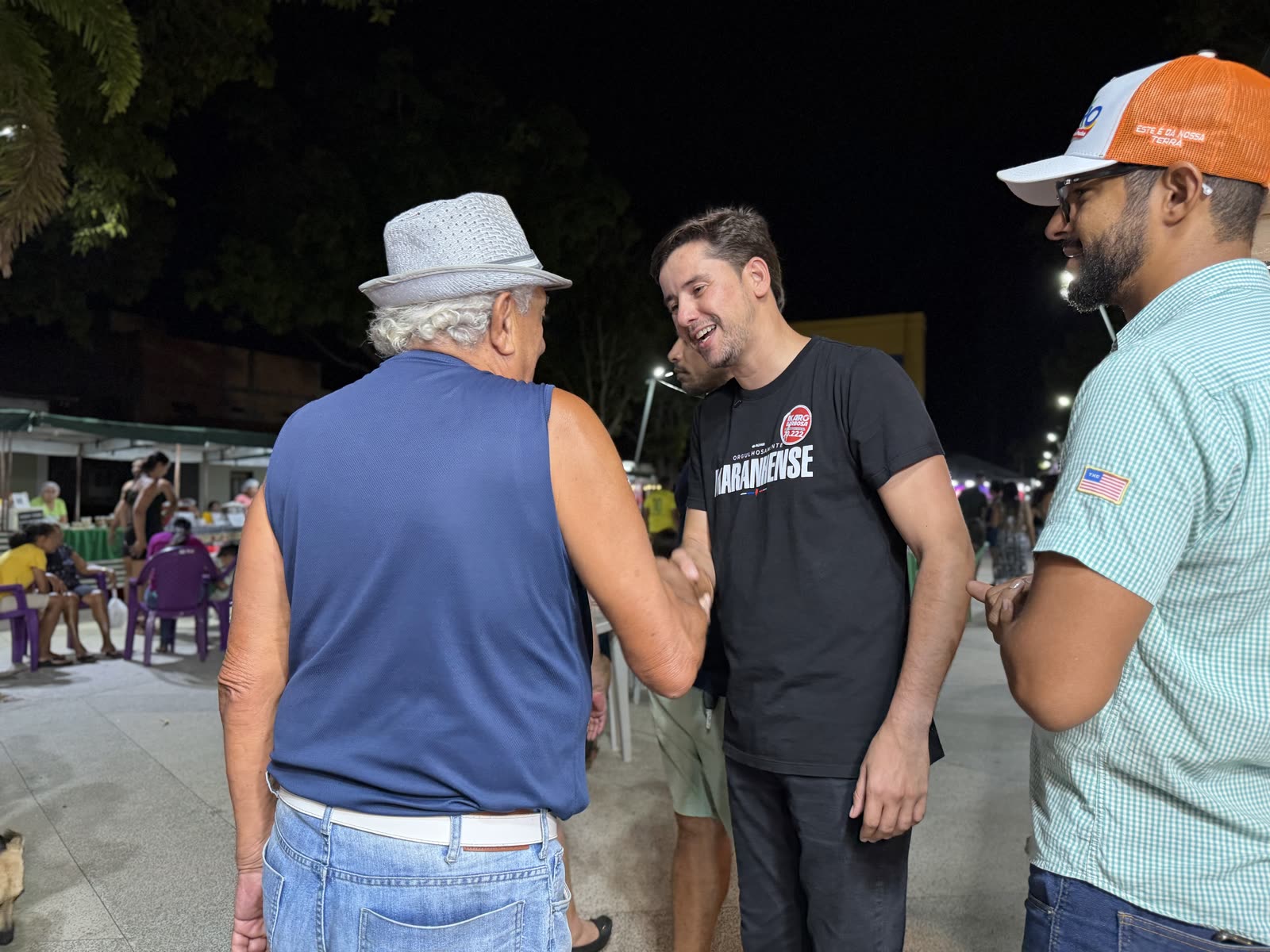 Ikaro Barbosa cumprimentando moradores na praça à noite